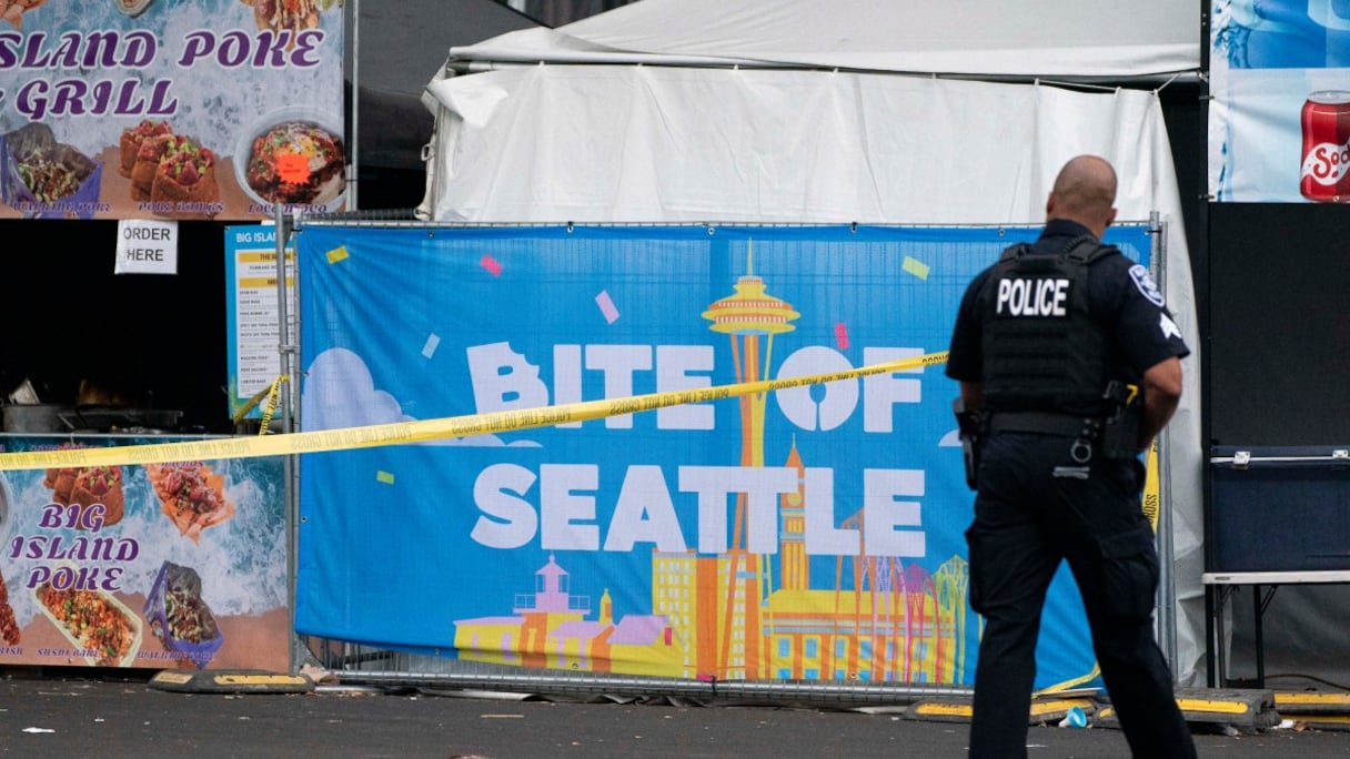 Un policier passe devant une affiche pour le festival culinaire Bite of Seattle, le 26 juillet 2026 à Seattle, dans l'État de Washington. Deux personnes sont mortes et plusieurs autres ont été blessées lors d'une fusillade de masse survenue lors de cet événement dimanche soir, au Seattle Center.